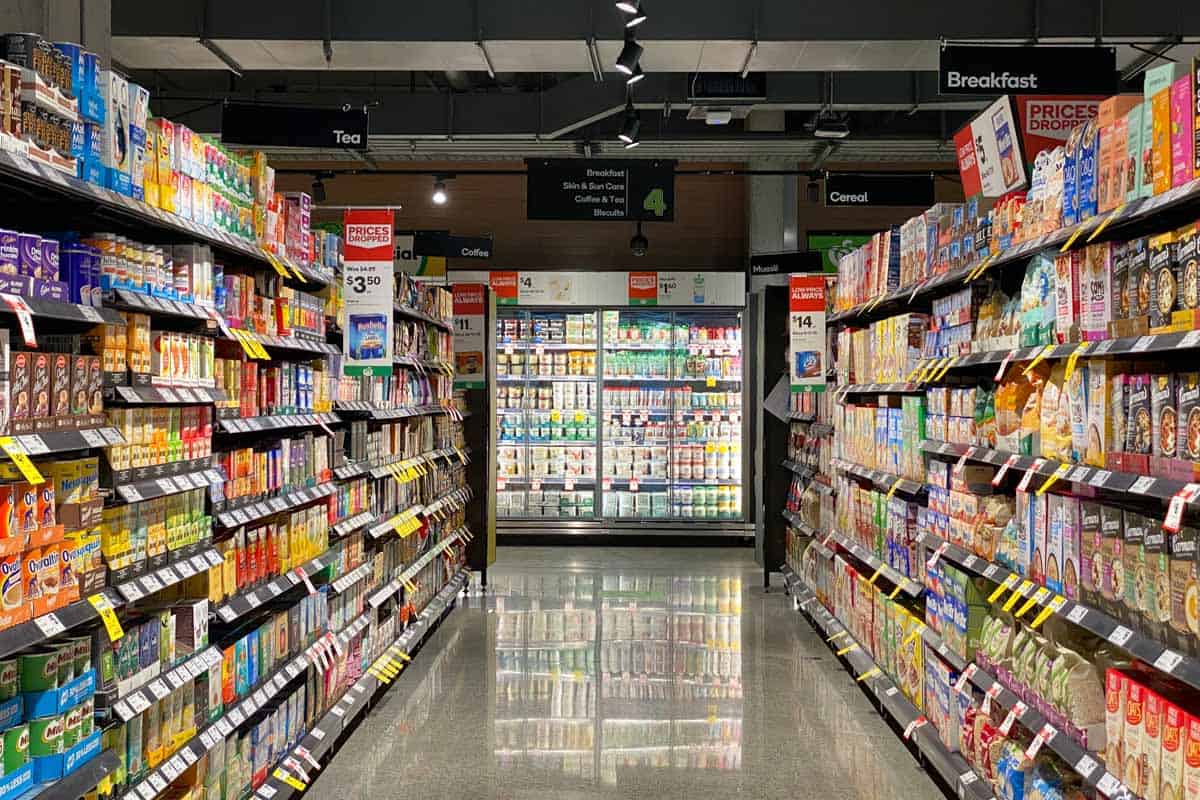 Supermarket aisle with refrigerator section at end.