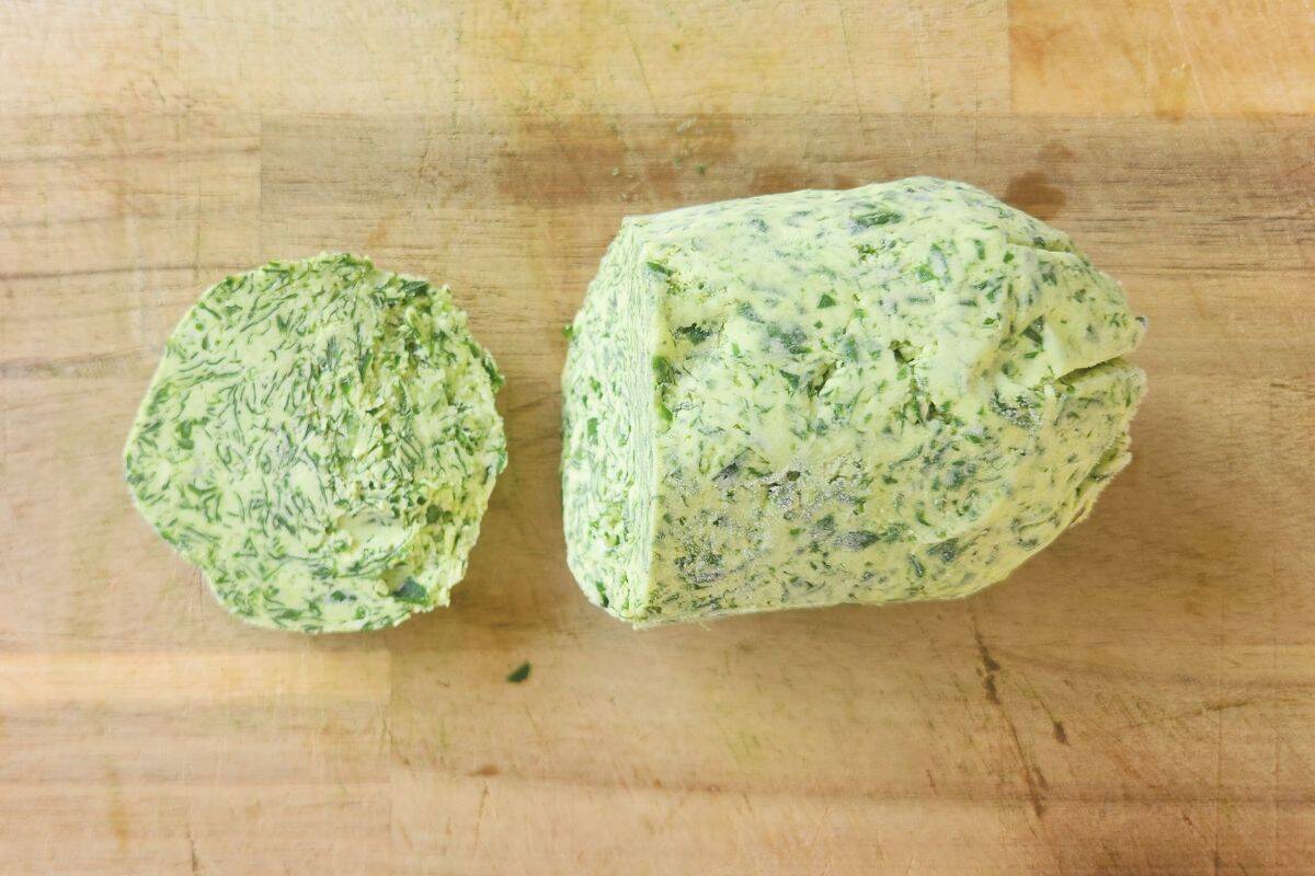 Overhead shot of homemade wild garlic butter being sliced on board