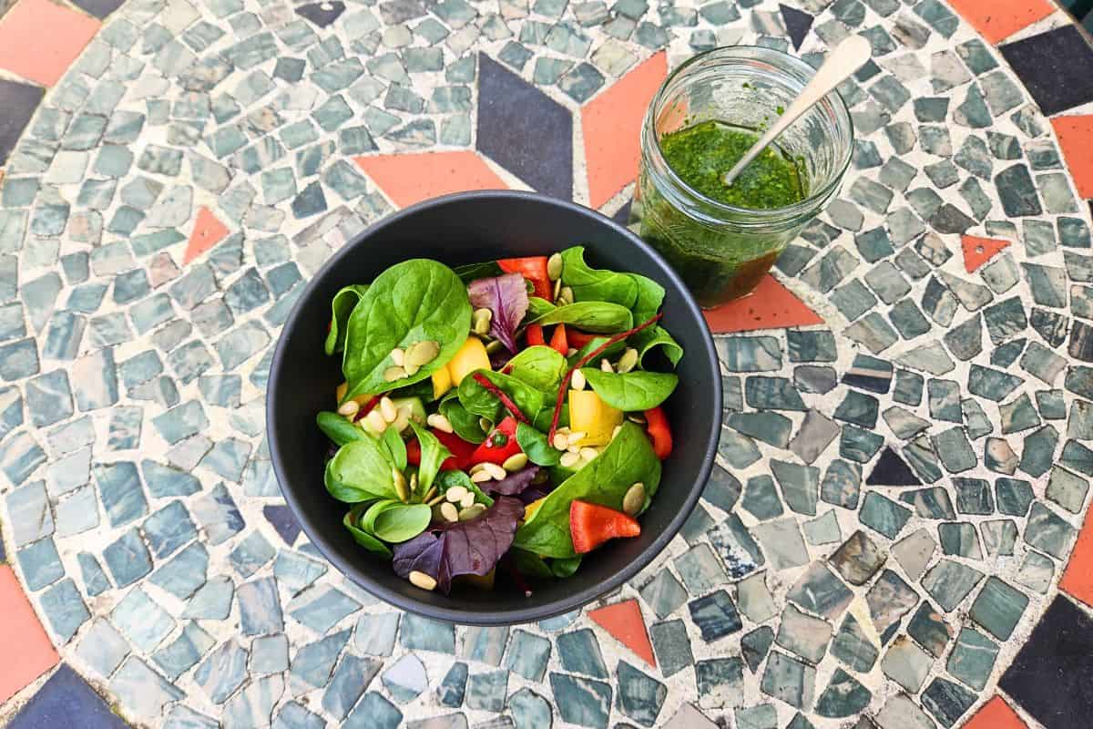 Jar of wild garlic sauce next to salad bowl