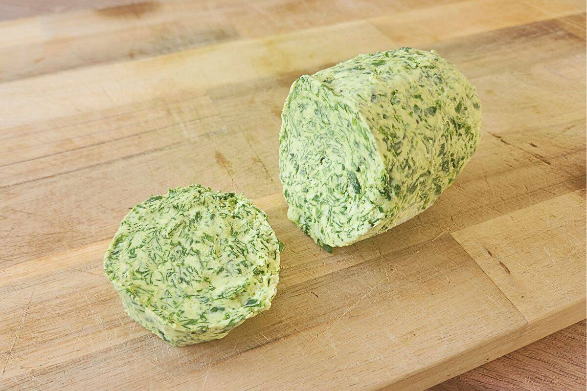 Wild garlic butter log with slice on wooden board