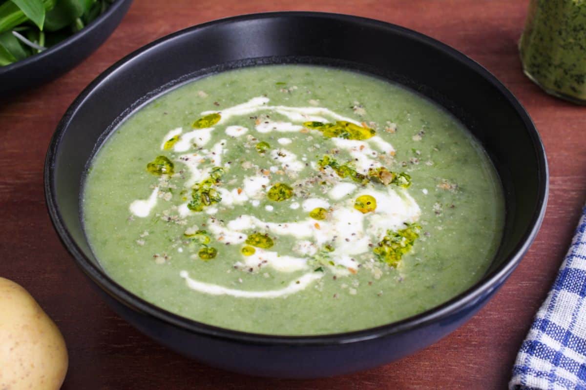Wild garlic soup in bowl with pesto, cream, and super seed mix