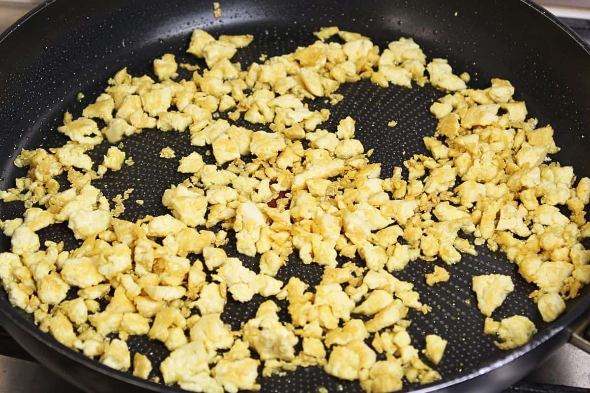 Torn tofu pieces frying in pan