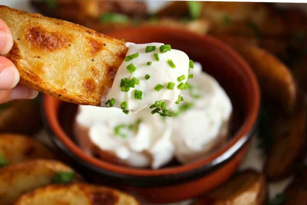 Baked potato wedge dipped in vegan sour cream with chives